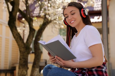 Happy young woman reading book in park