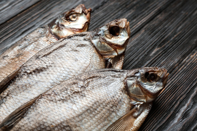 Photo of Tasty dried fish on black wooden table, closeup