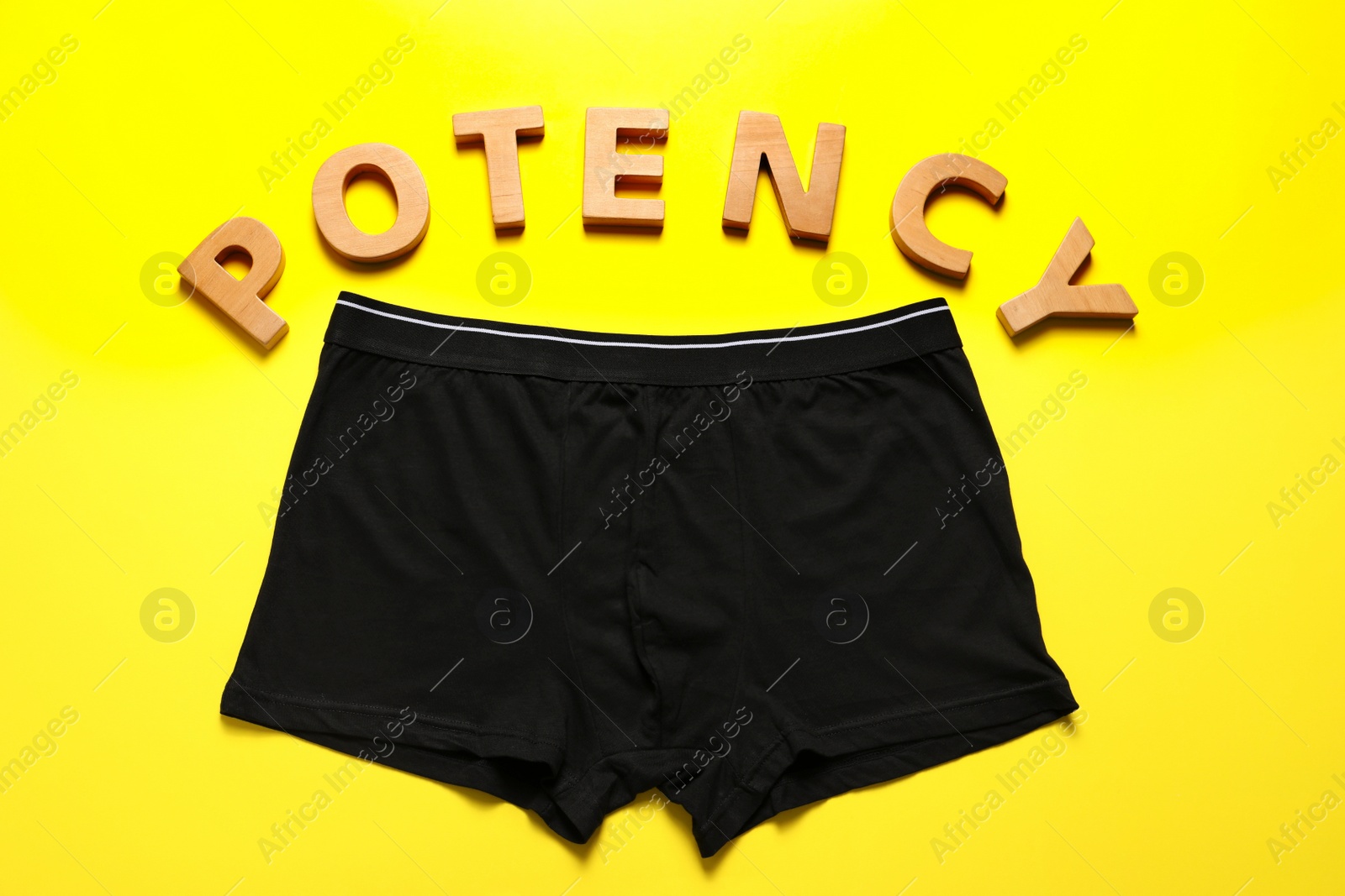 Photo of Men underwear and word Potency made of wooden letters on yellow background, flat lay