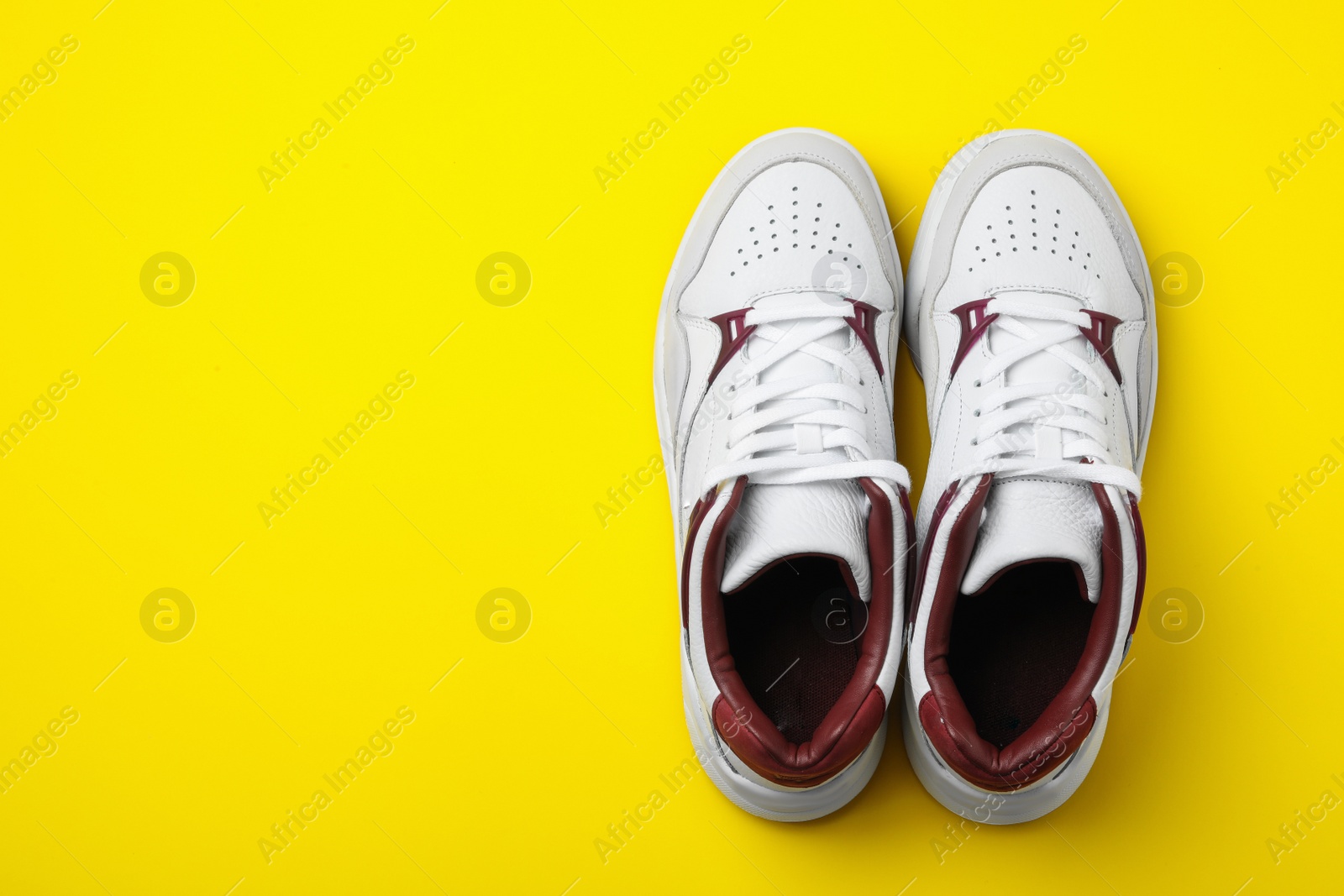 Photo of Pair of stylish shoes on yellow background, top view. Space for text