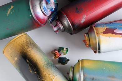 Many spray paint cans on white background, flat lay