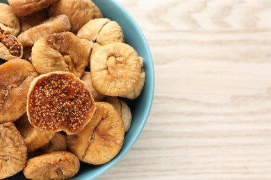 Photo of Bowl with tasty dried figs on white wooden table, top view. Space for text