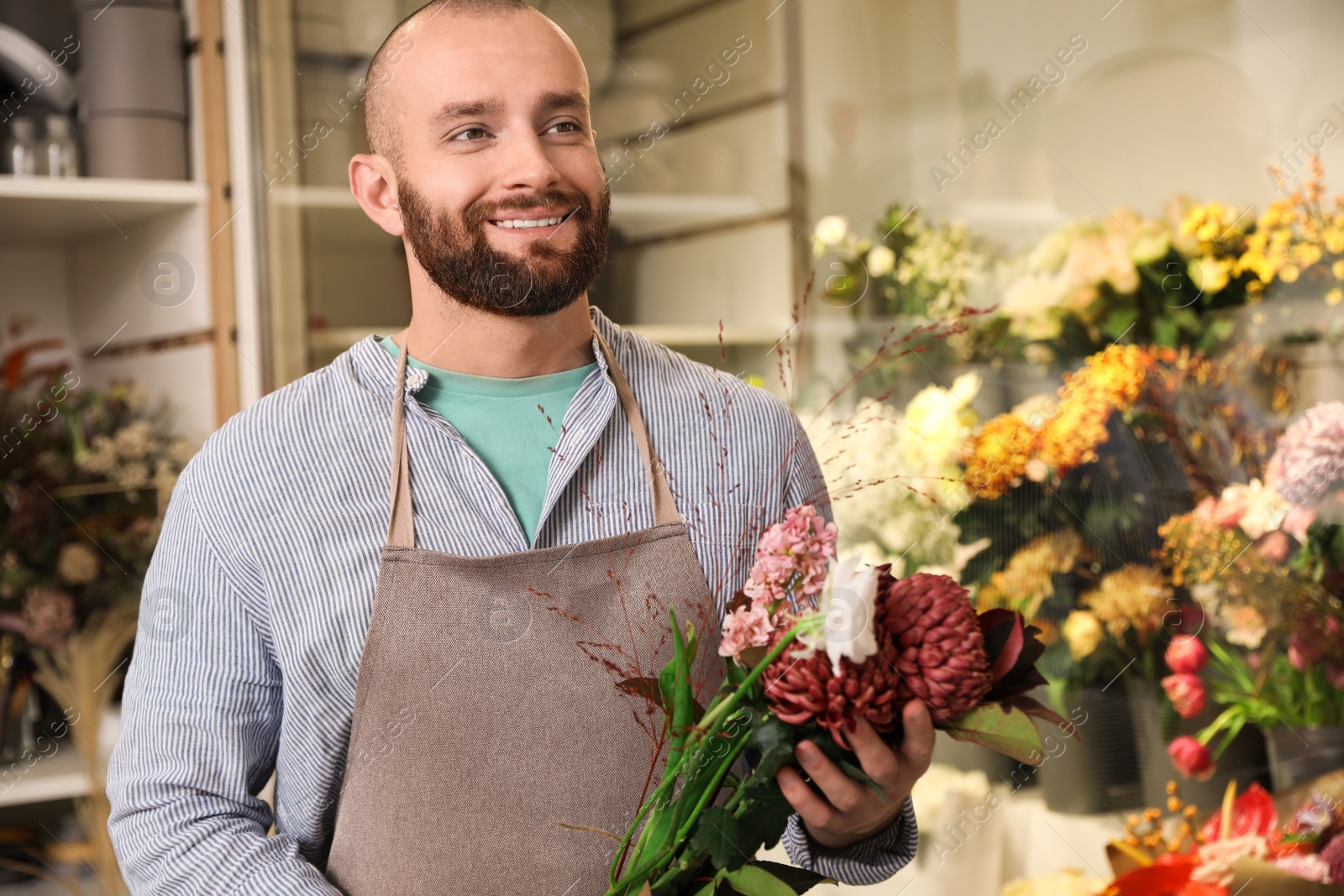 Photo of Professional florist with bouquet of fresh flowers in shop