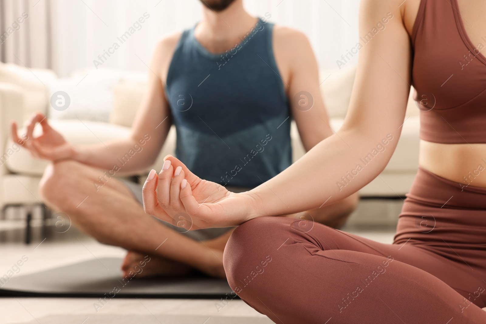 Photo of Couple in sportswear meditating together at home, closeup. Harmony and zen