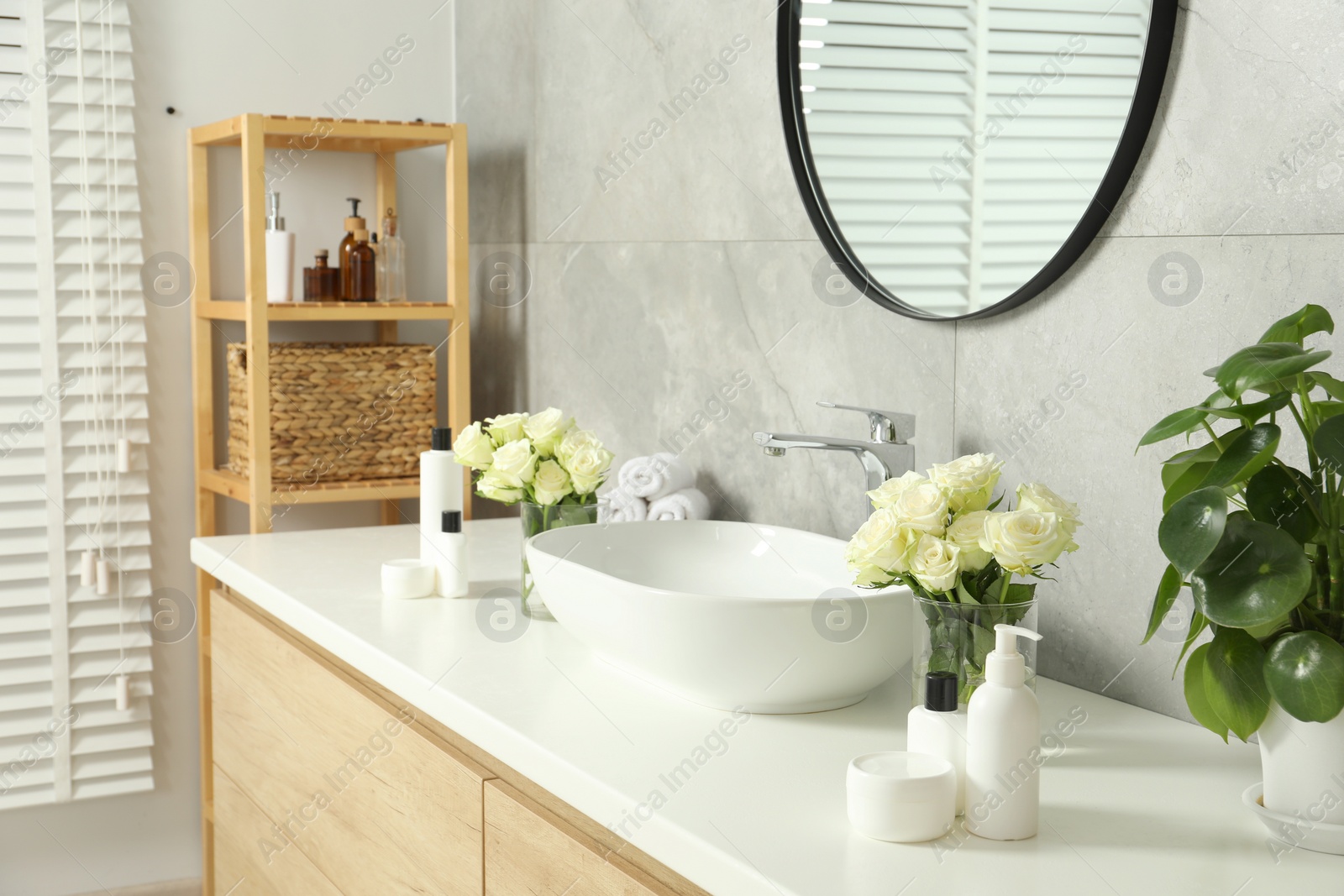 Photo of Beautiful roses and bath accessories near sink in bathroom