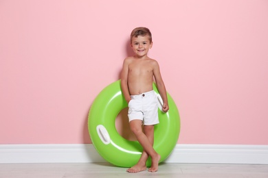 Photo of Cute little boy with bright inflatable ring near color wall