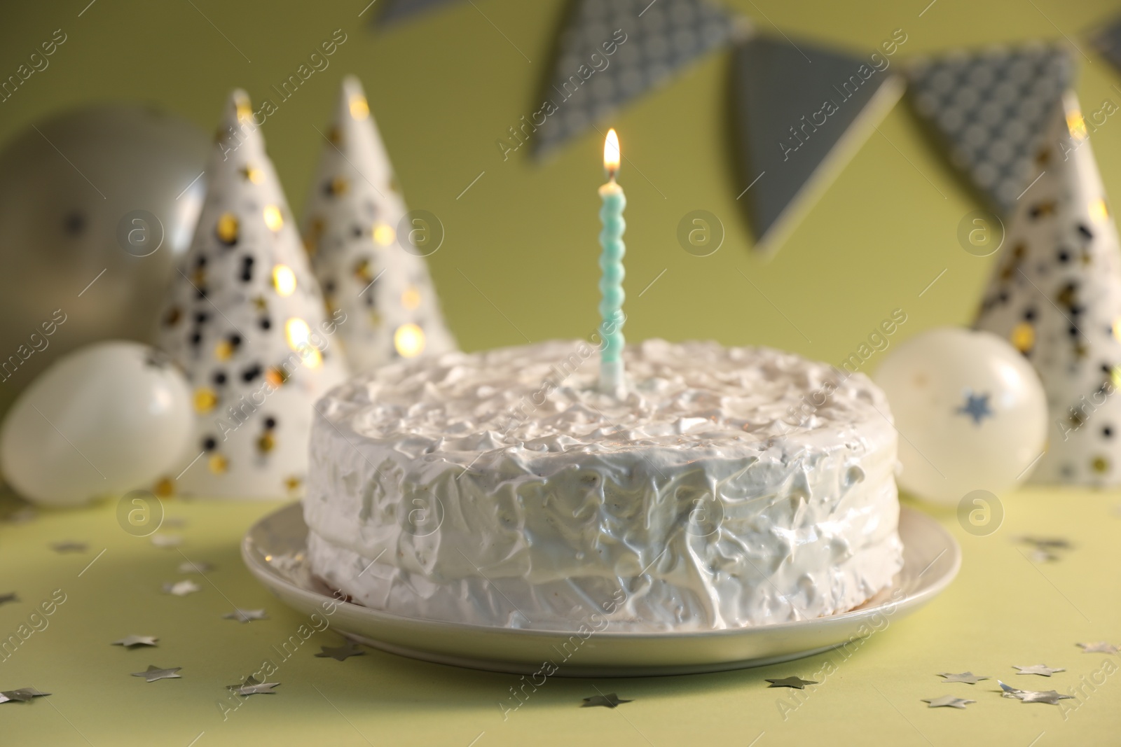 Photo of Tasty cake with burning candle on green background, closeup