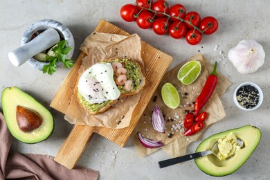 Photo of Delicious sandwich with guacamole, shrimps, fried egg and ingredients on light grey table, flat lay