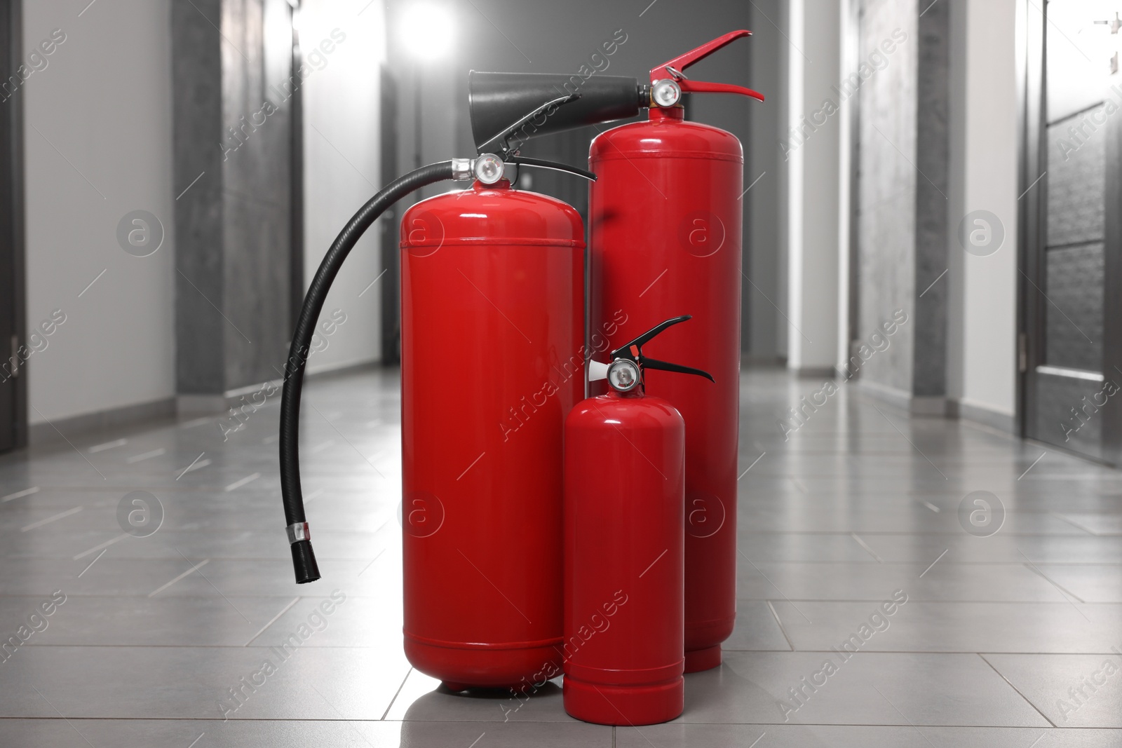 Photo of Three new red fire extinguishers in hall