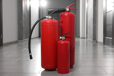 Photo of Three new red fire extinguishers in hall