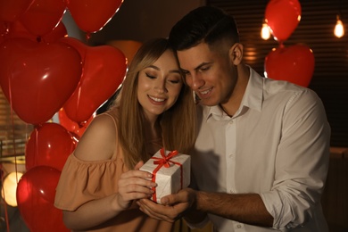 Photo of Lovely couple with gift in room. Valentine's day celebration