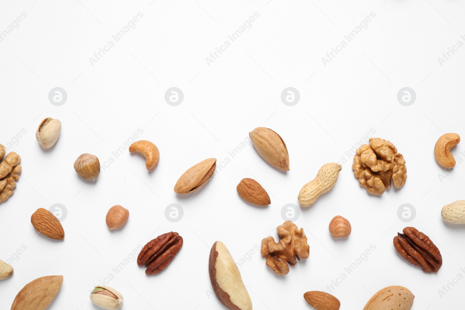 Photo of Different delicious nuts on white background, flat lay. Space for text