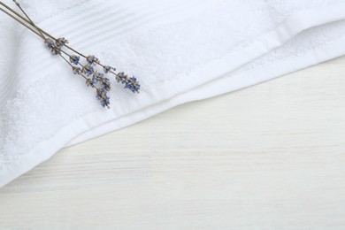 Photo of White terry towel and lavender flowers on light wooden table, top view. Space for text