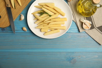 Photo of Fresh baby corn cobs on blue wooden table, flat lay. Space for text