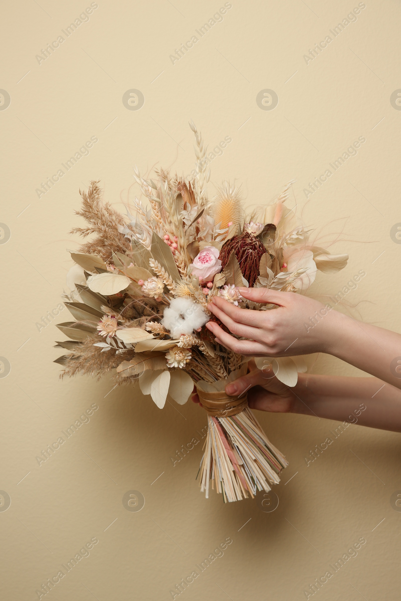 Photo of Woman holding beautiful dried flower bouquet on beige background, closeup