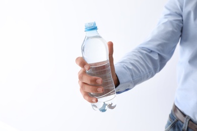 Man holding bottle of pure water on white background, closeup. Space for text