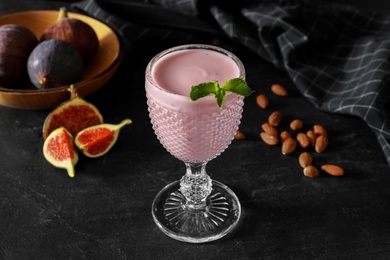 Photo of Delicious fig smoothie in glass on black table