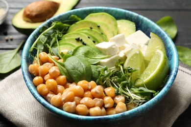 Photo of Delicious avocado salad with chickpea on black wooden table