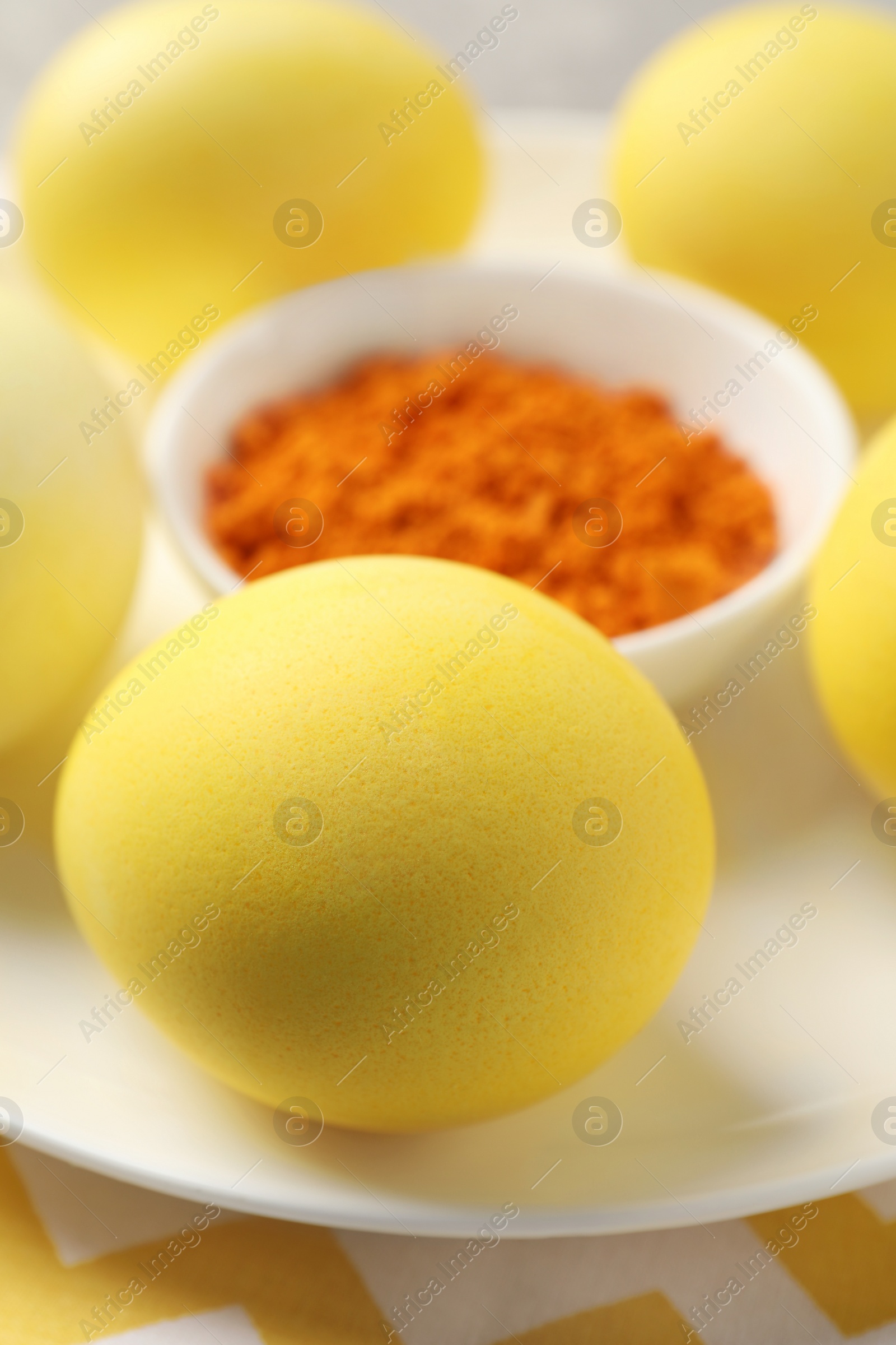 Photo of Yellow Easter eggs painted with natural dye and turmeric powder in bowl on table, closeup