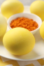 Yellow Easter eggs painted with natural dye and turmeric powder in bowl on table, closeup