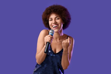 Photo of Curly young woman with microphone singing on purple background