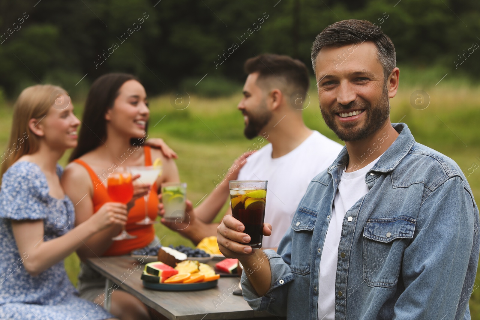 Photo of Friends having cocktail party outdoors. Happy man with glass of drink, selective focus