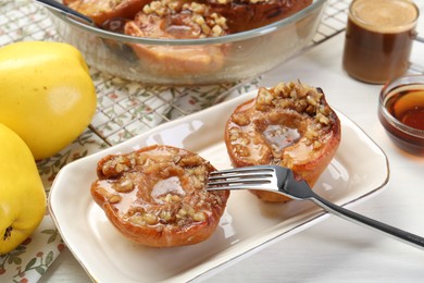 Photo of Delicious quinces baked with honey and walnuts on white table