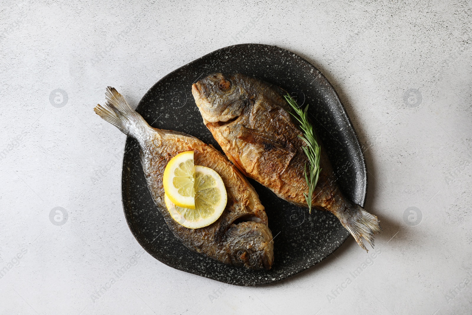 Photo of Delicious dorado fish with rosemary and lemon on light grey table, top view