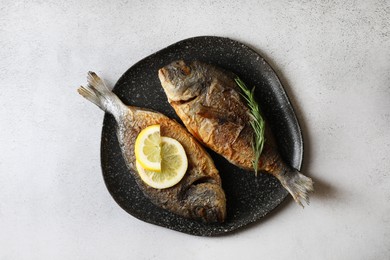 Delicious dorado fish with rosemary and lemon on light grey table, top view