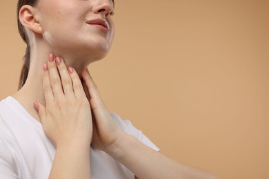 Photo of Woman touching her neck on beige background, closeup. Space for text