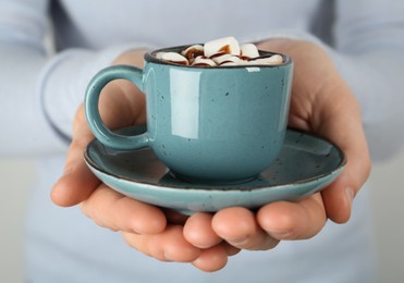 Photo of Woman holding cup of delicious hot chocolate with marshmallows and syrup, closeup