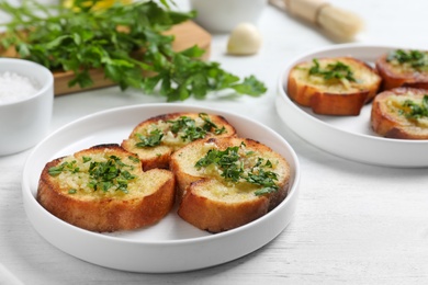 Photo of Slices of toasted bread with garlic and herb on white wooden table