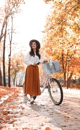 Beautiful happy woman with bicycle in autumn park