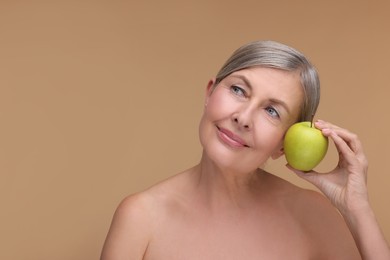 Photo of Beautiful woman with fresh apple on beige background, space for text. Vitamin rich food