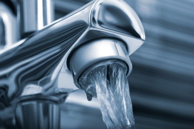 Image of Water flowing from tap on blurred background, closeup