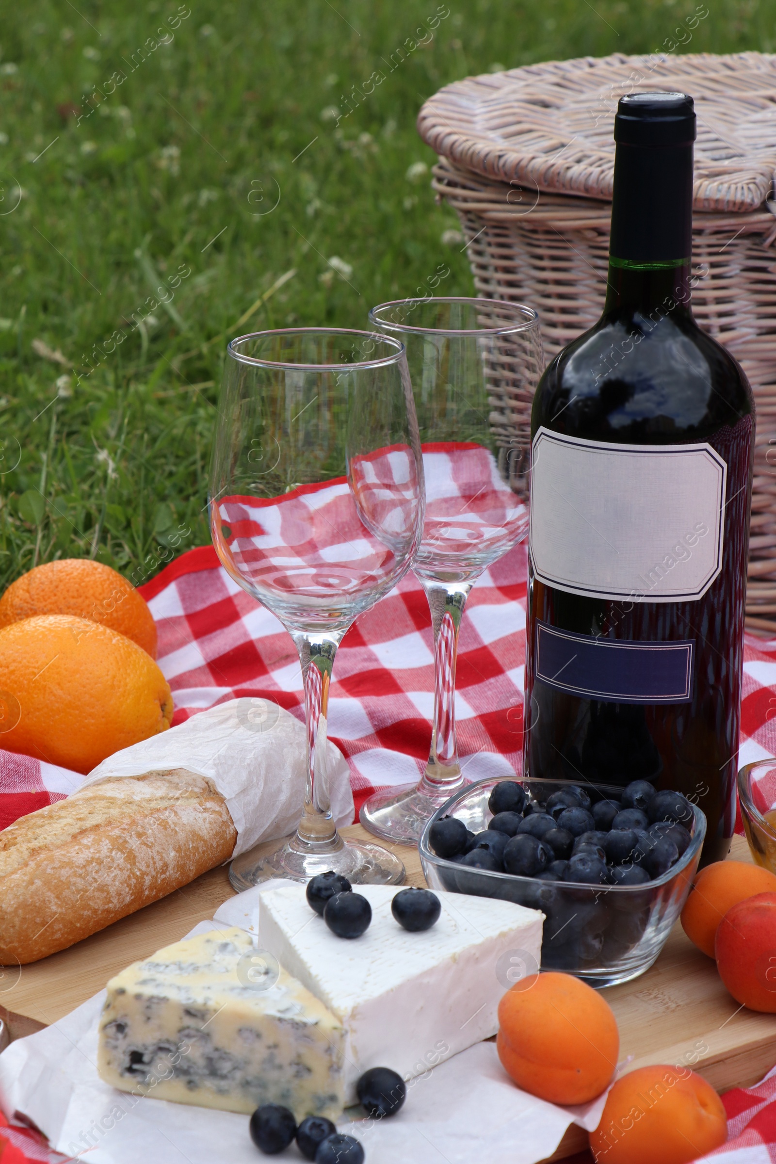 Photo of Picnic blanket with delicious food and wine outdoors on summer day