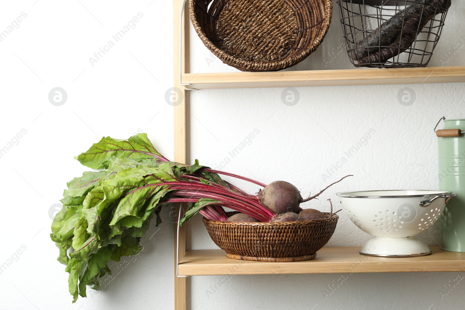 Photo of Raw ripe beets in wicker bowl on shelf indoors