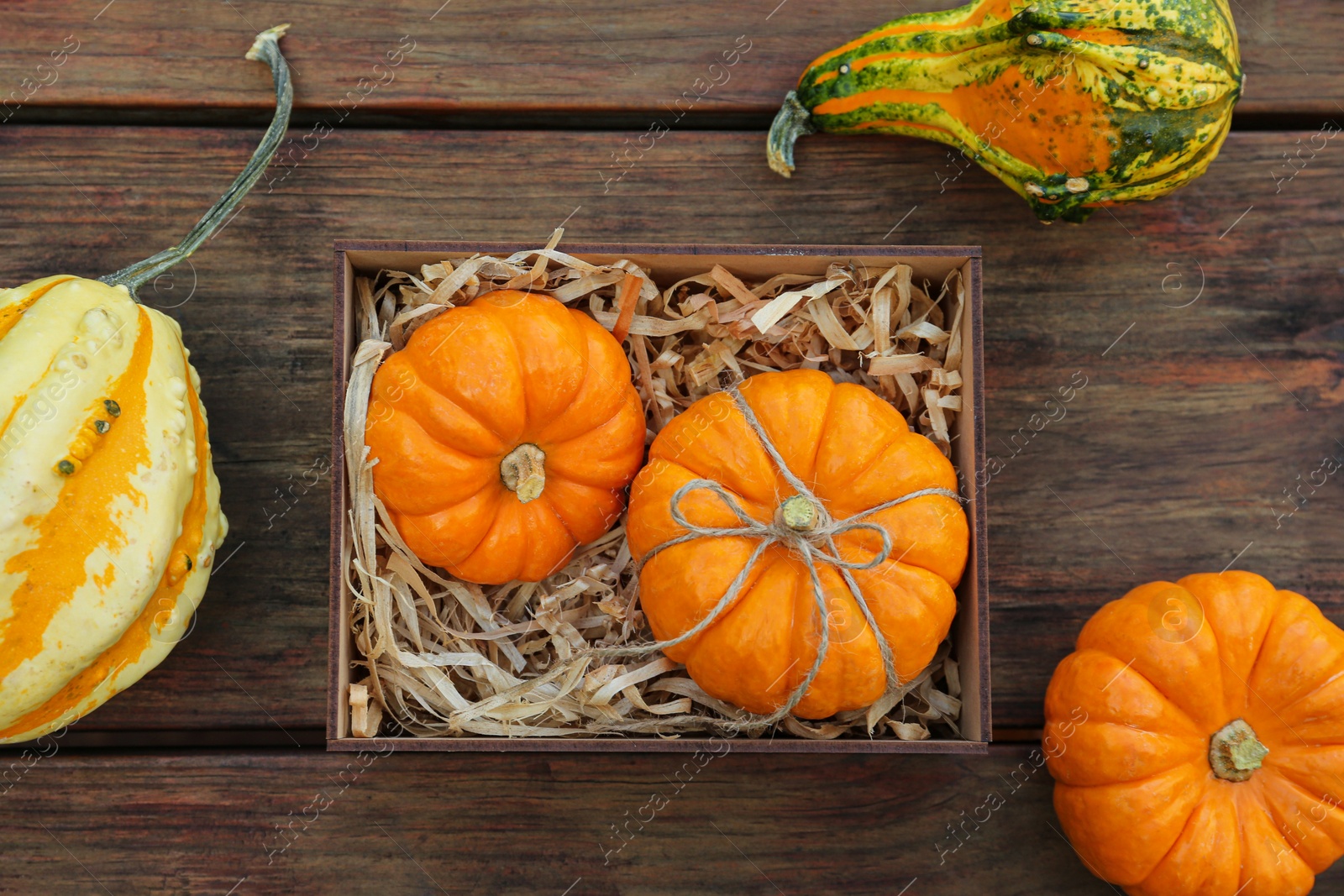 Photo of Crate and ripe pumpkins on wooden table, flat lay