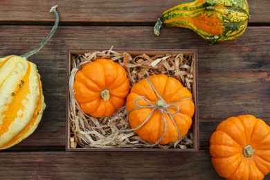 Photo of Crate and ripe pumpkins on wooden table, flat lay
