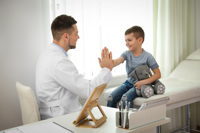 Photo of Children's doctor working with little patient in clinic