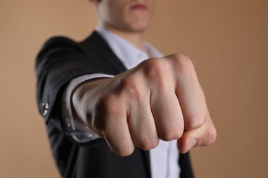 Photo of Businessman showing fist with space for tattoo on beige background, selective focus