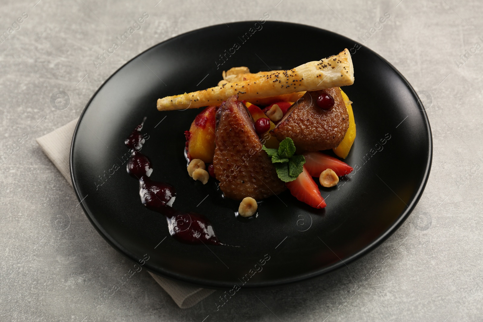 Photo of Plate with delicious chicken, parsnip and strawberries on grey table. Food stylist