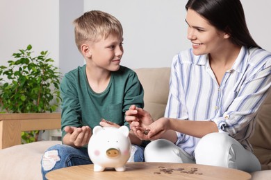 Photo of Boy and his mother with piggy bank at home