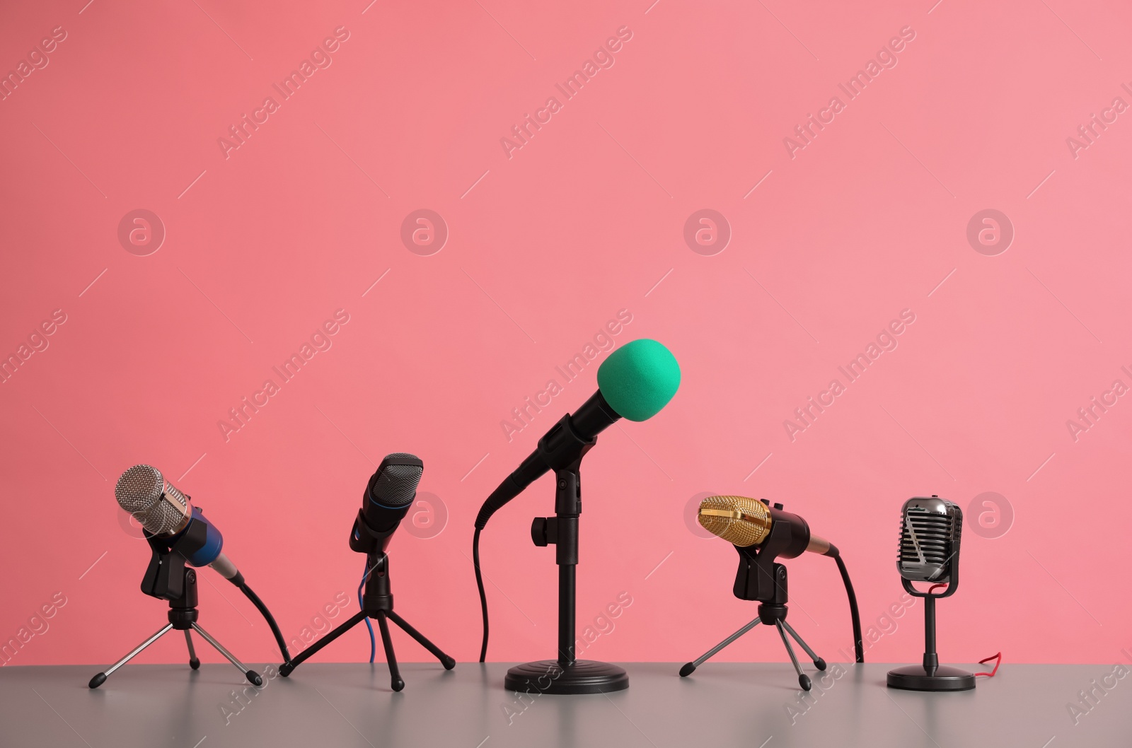 Photo of Microphones on table against pink background. Journalist's work