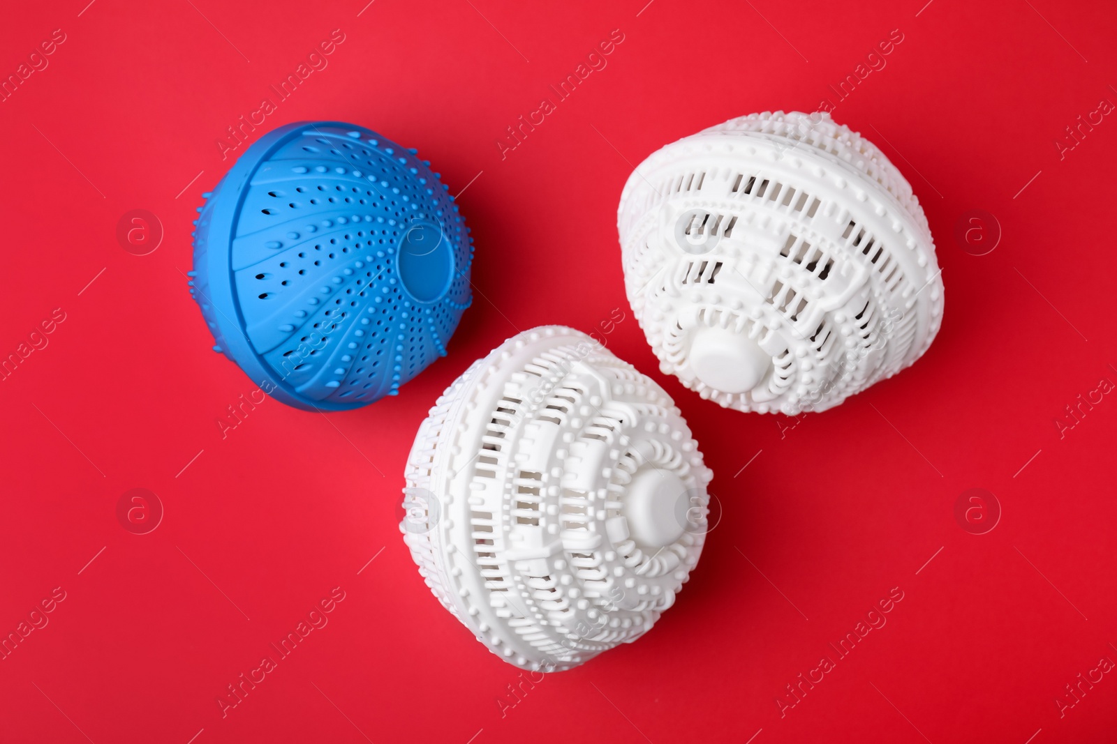 Photo of Dryer balls for washing machine on red background, flat lay