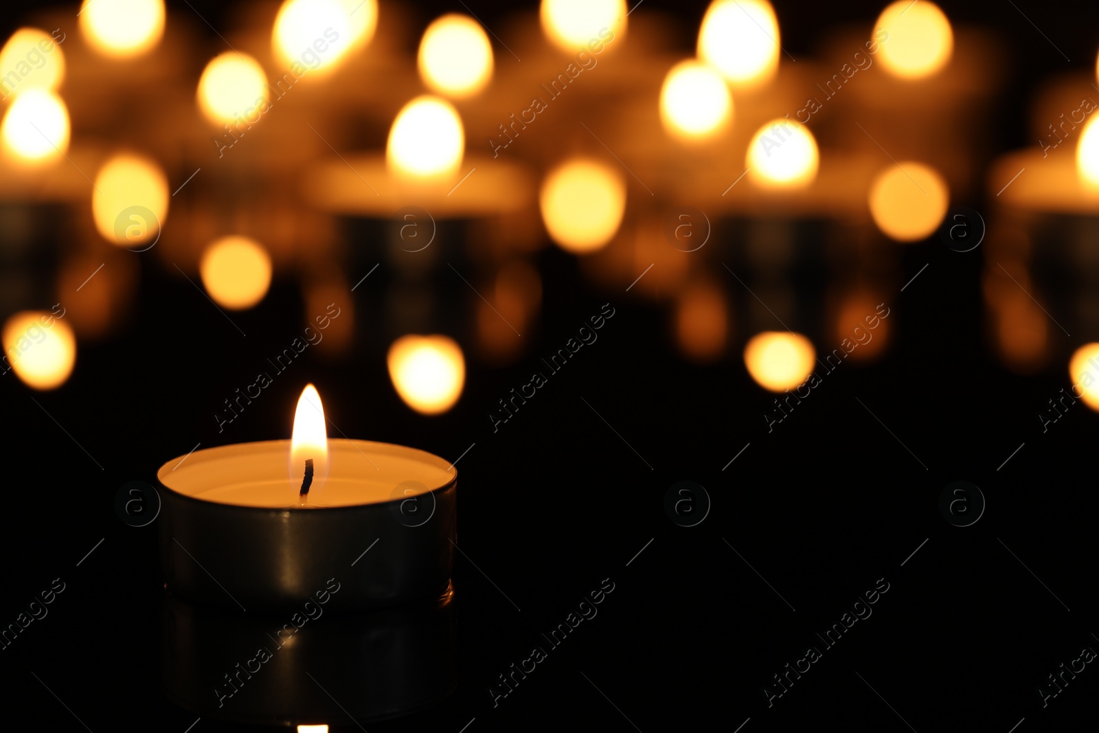 Photo of Burning candle on surface in darkness, closeup. Space for text