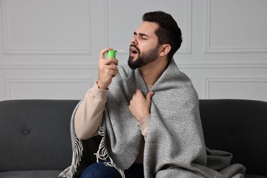 Young man using throat spray at home