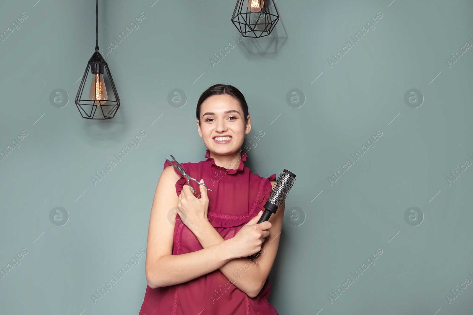 Photo of Professional hairdresser with scissors and brush on color background