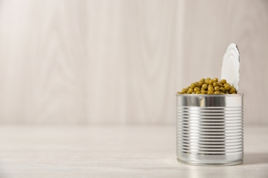 Photo of Open tin can of green peas on light table, space for text