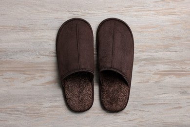 Photo of Pair of brown slippers on white wooden floor, top view